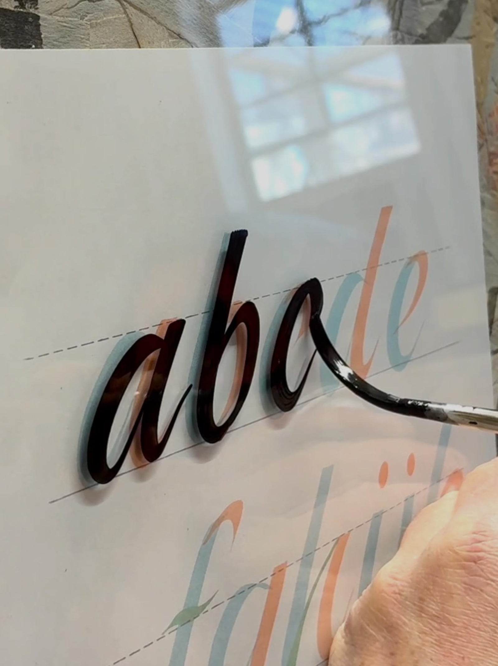 Hand holding a metallic letter 'a' over a paper with colorful text